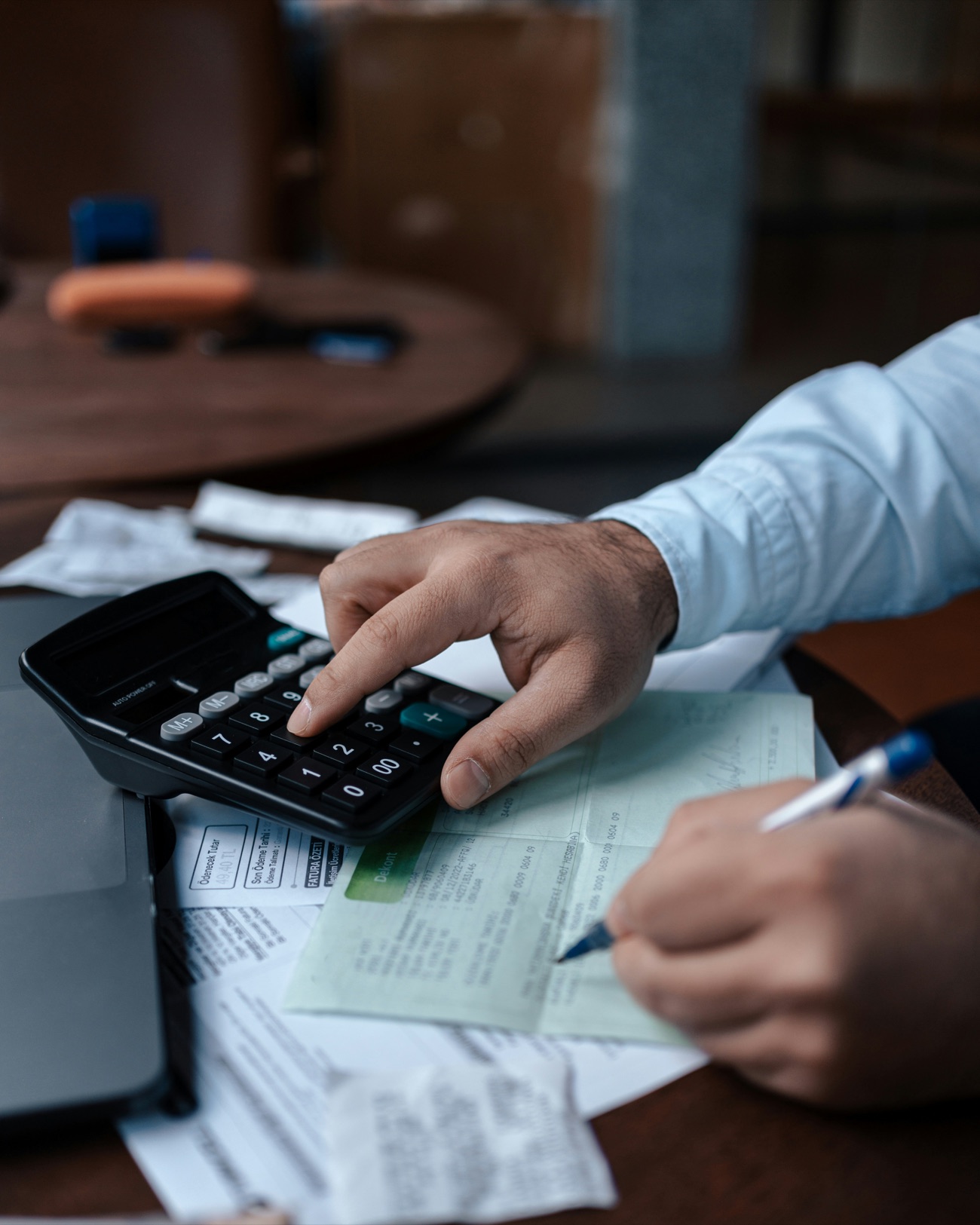 An accountant reconciling invoices and receipts with a calculator, signing off a bank advice.