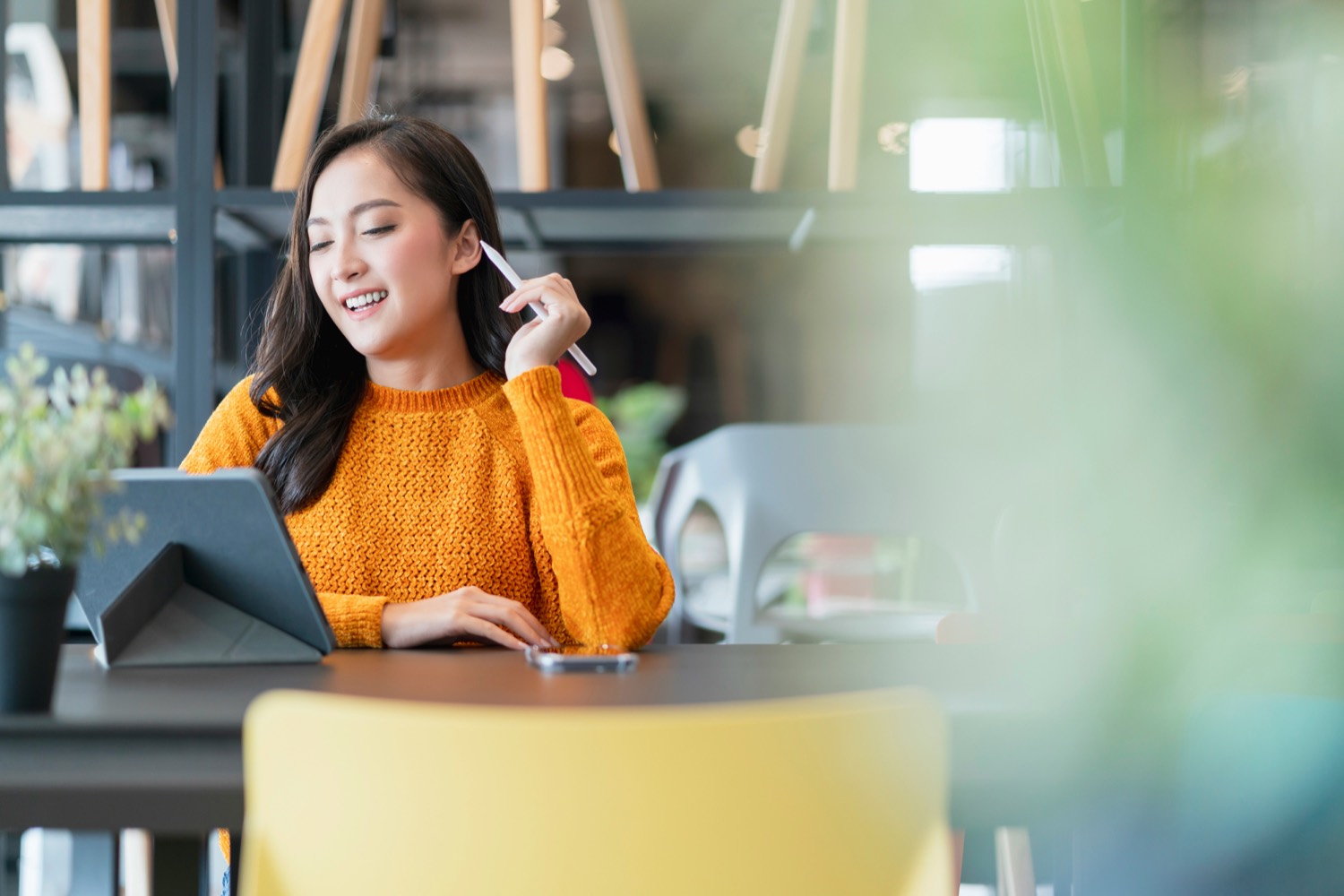 A contractor smiling while working on a tablet at a café.