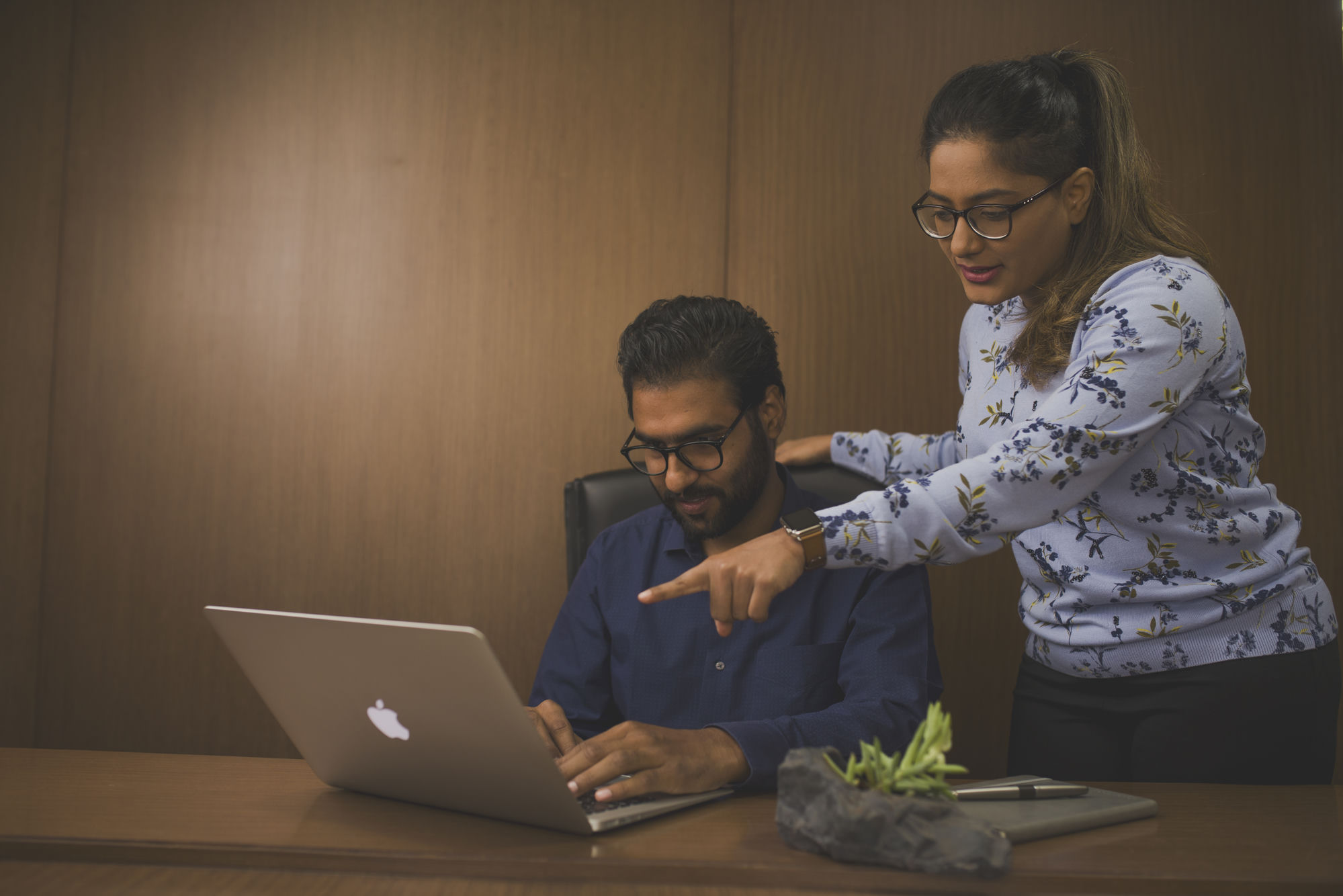 A new hire and a colleague reviewing the onboarding portal together at a laptop.